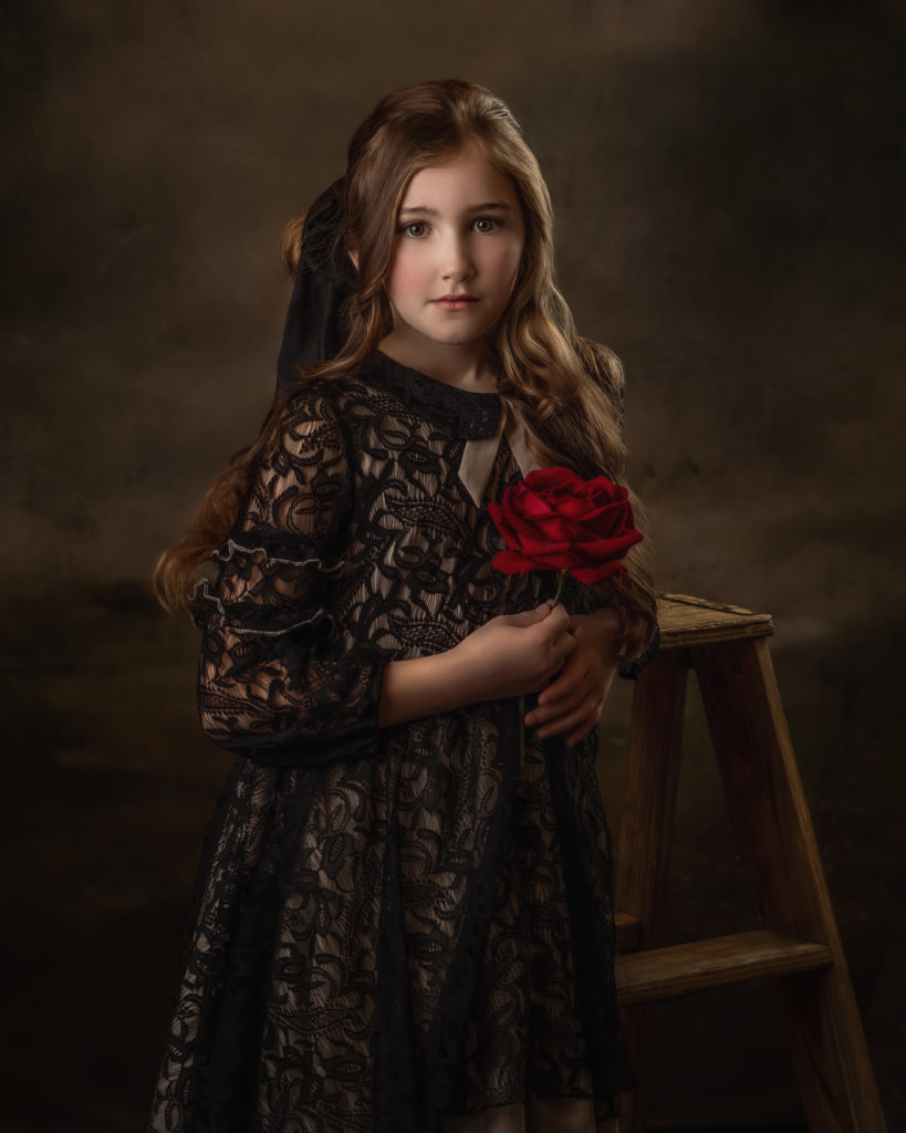 Girl in vintage dress holding a red rose