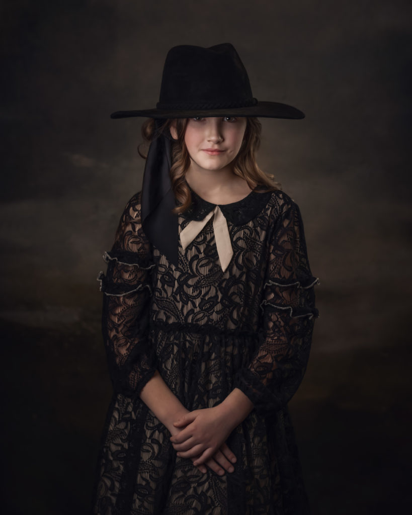 Girl in vintage dress wearing black hat over eyebrows
