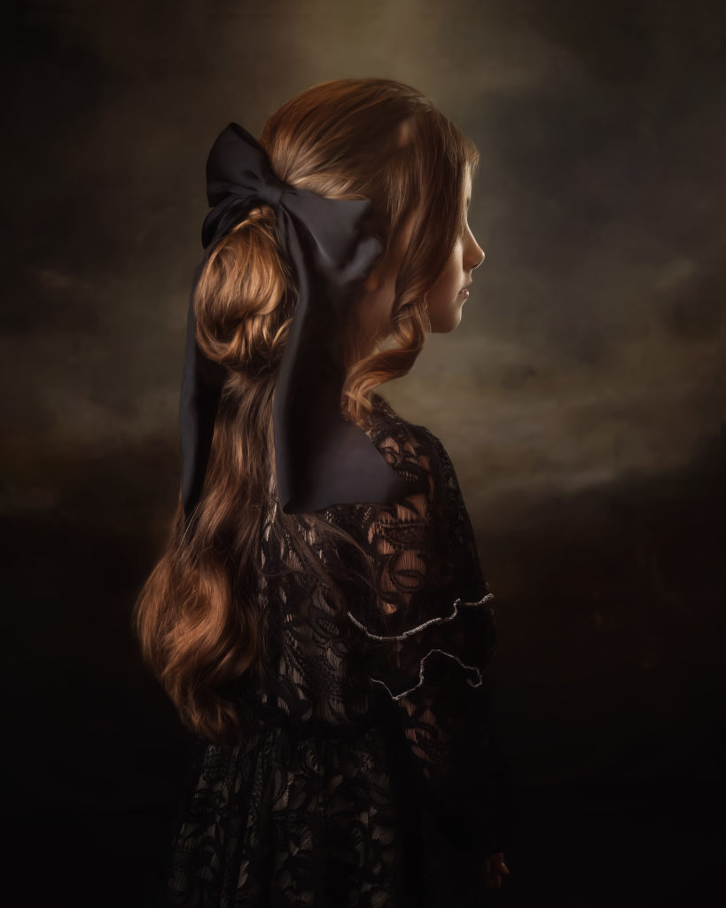 Girl in vintage dress showing hairstyle with black bow on back of head